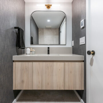 North Vancouver Modern Gray Powder Room North Vancouver stylish powder room featuring a floating light wood vanity with integrated sink, arched mirror, black fixtures, textured dark wallpaper, and a minimalist design with warm ambient lighting.