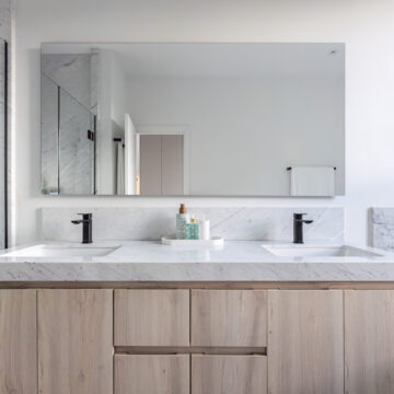 North Vancouver Primary Ensuite Custom Vanity with Dual Sinks North Vancouver primary ensuite renovation with a contemporary bathroom featuring a double sink vanity with light wood cabinetry, white countertops, matte black faucets, and a large wall-mounted mirror reflecting a clean, minimalist design.