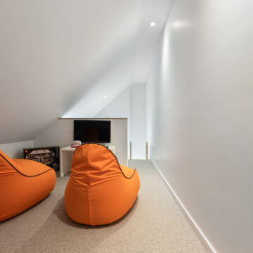 North Vancouver Kid's Loft with Minimalist Design Loft play space tucked under a sloped ceiling with bean bag chairs for gaming.
